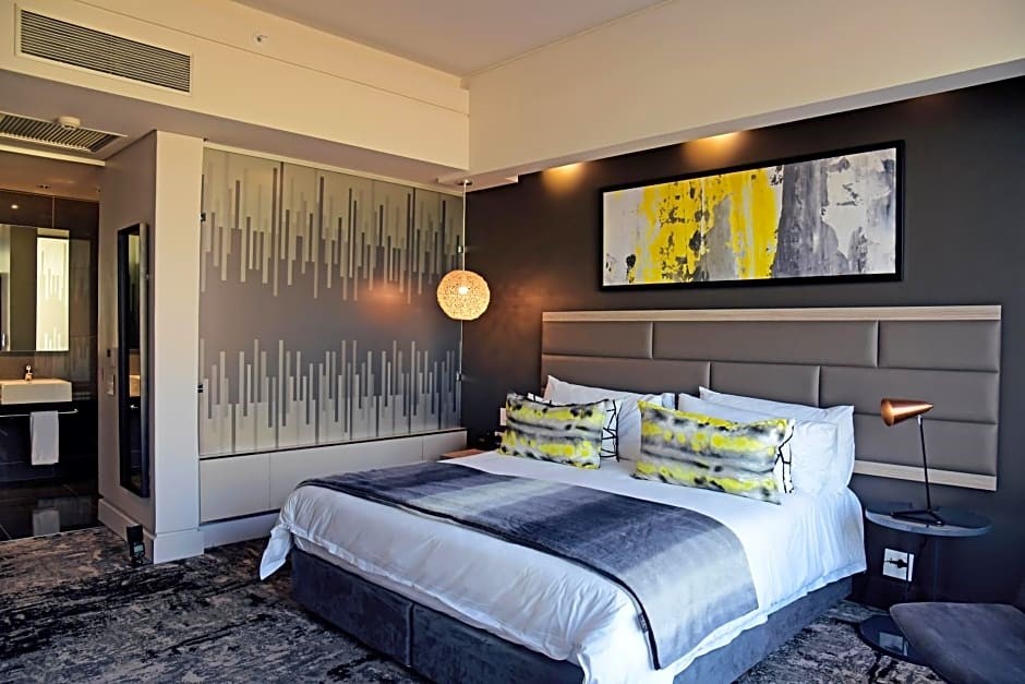 A modern hotel room with a large bed, abstract artwork, and a stylish lamp. A modern hotel room with a large bed, abstract artwork, and a stylish lamp.