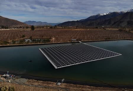 Large floating solar panel in man made body of water surrounded by mountains