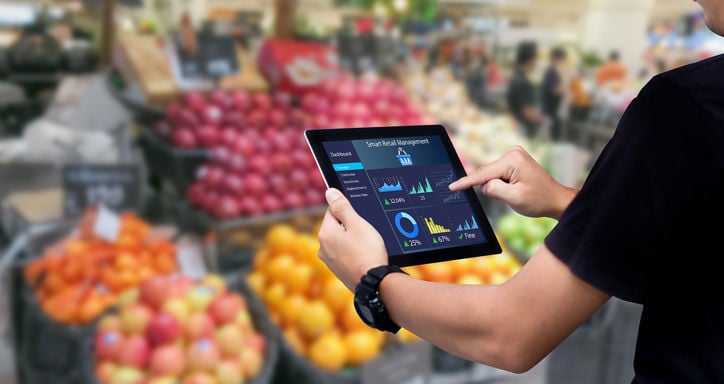 Person using a tablet showing a "Smart Retail Management" dashboard in a supermarket.