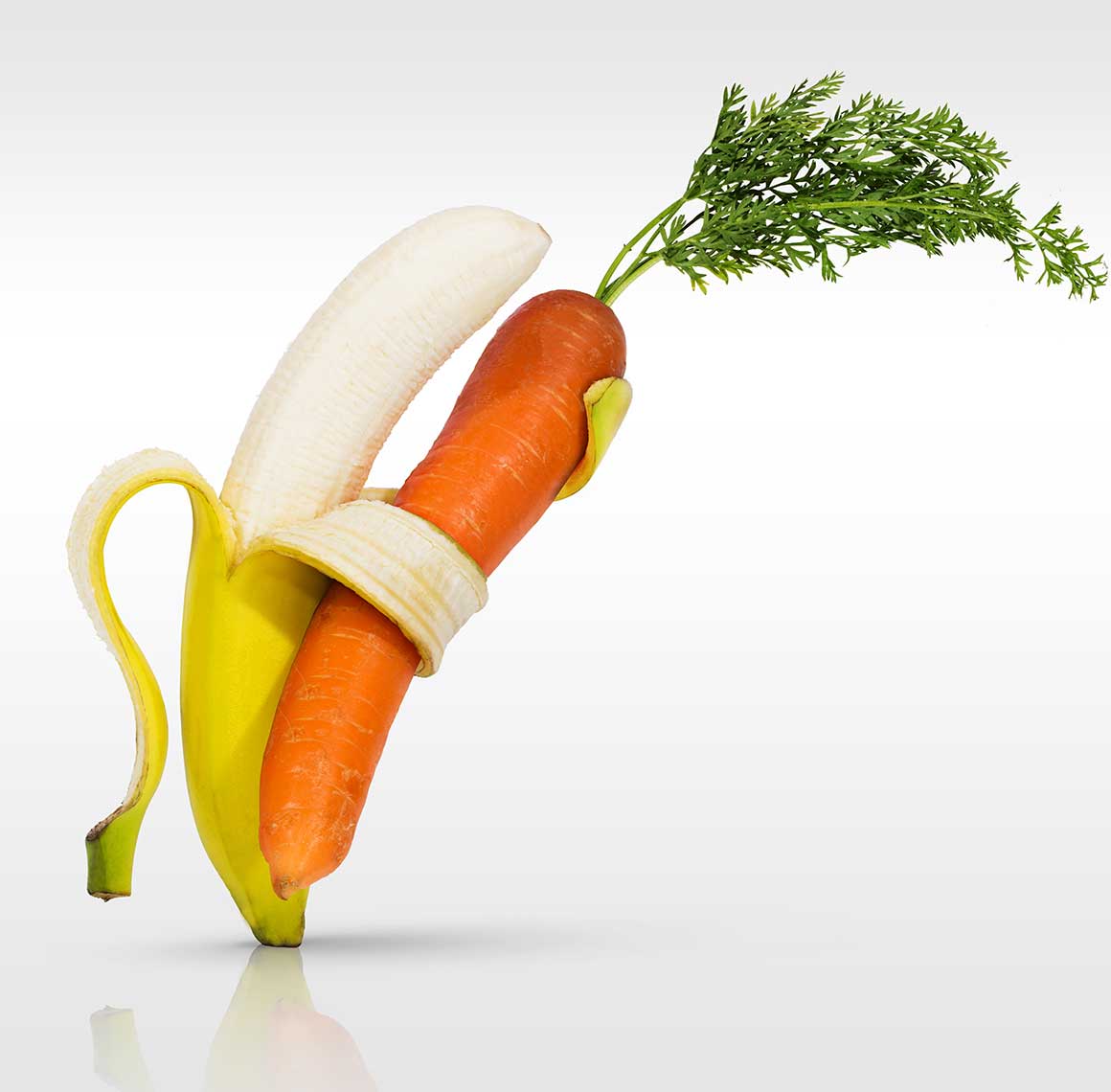 A carrot wrapped in a partially peeled banana.