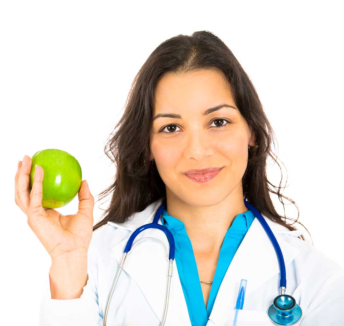 Person in a medical coat holding a green apple with a stethoscope around their neck.