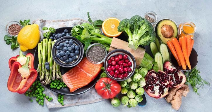 An assortment of fresh fruits, vegetables, salmon, and seeds on display.
