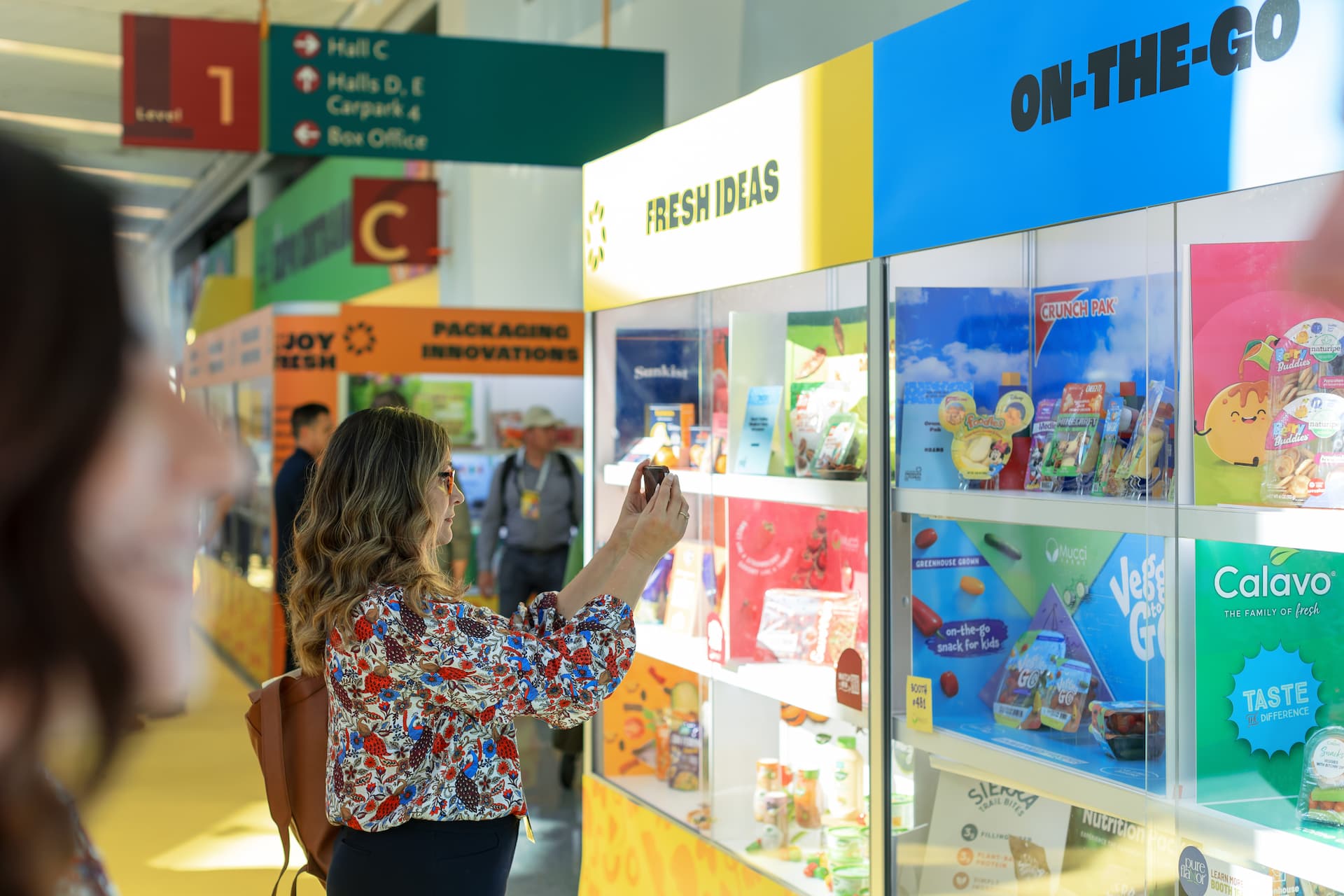 A woman takes a photo with her phone of display items at Fresh Ideas 2023.