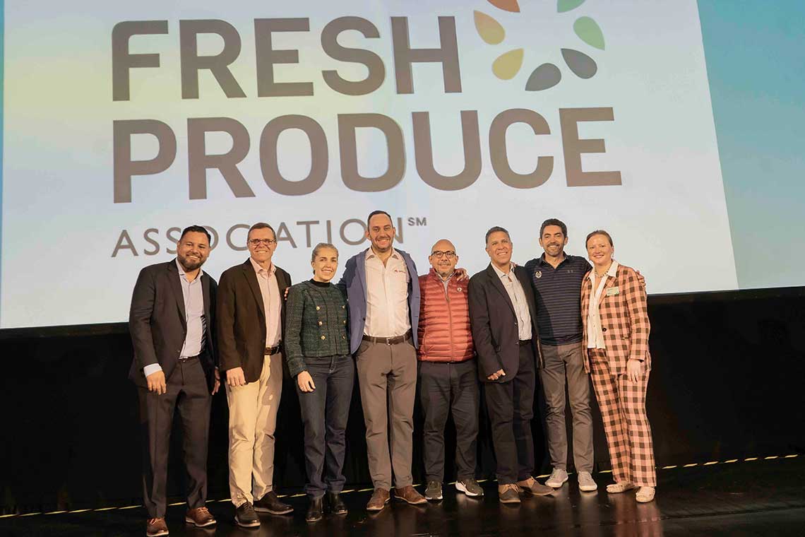 A group of nine people standing in front of a screen displaying "FRESH PRODUCE ASSOCIATION" logo.
