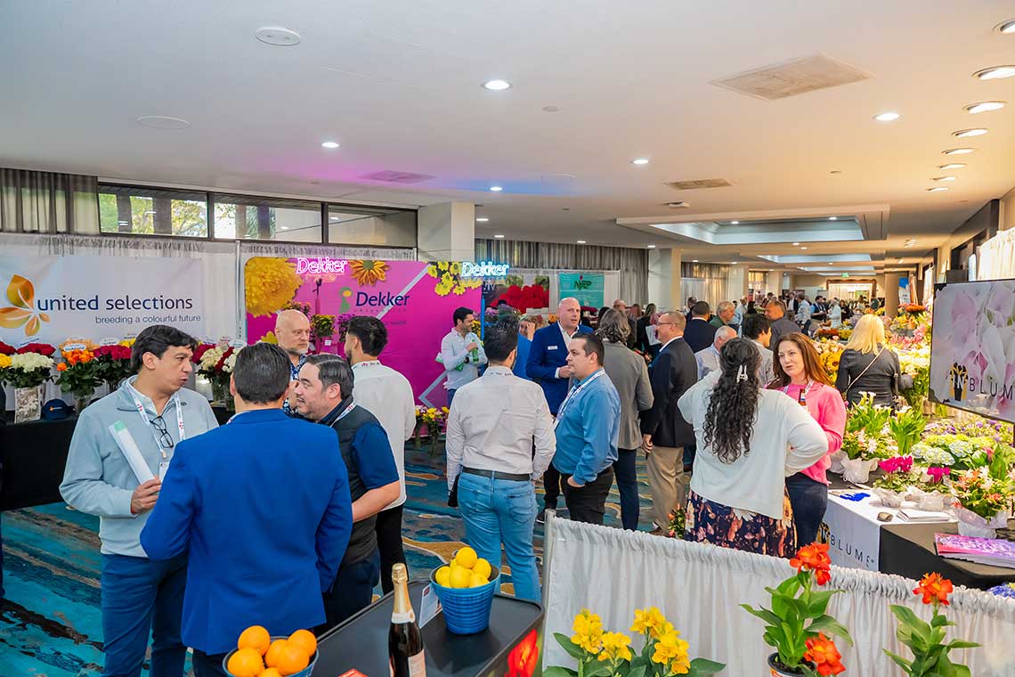 People attending a floral trade exhibition with multiple flower displays and vendor booths.