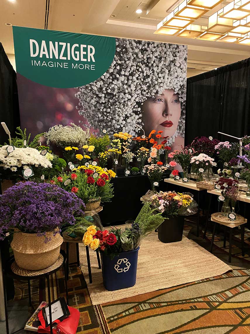 Floral display booth with "DANZIGER" banner and various colorful flowers.