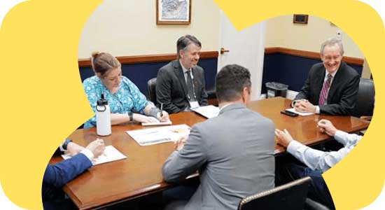 A group of six people in a meeting around a conference table.