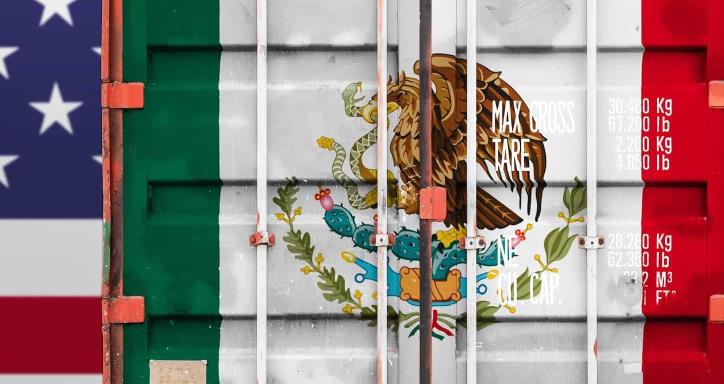 Large America flag in background with the Mexico flag painted on the back of a semi truck in the forefront
