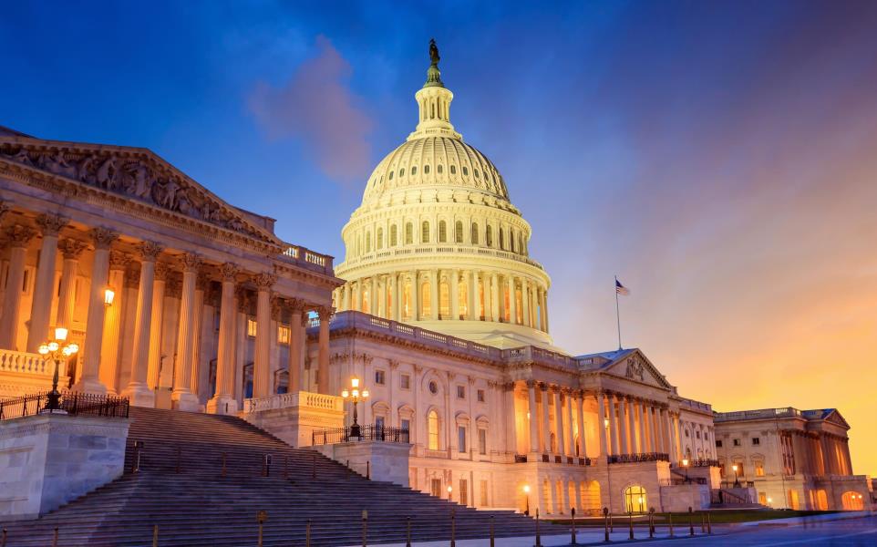 US Capitol glowing during sunset with the sun setting to the right 