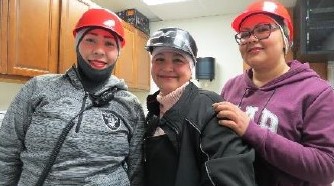 Three women in hardhats pose as a group.