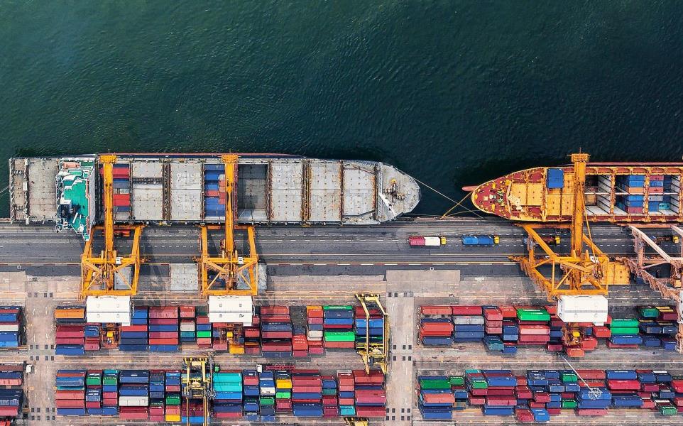 Aerial view of a container ship in export and import business and logistics. Shipping cargo to harbor by crane. Water transport International.