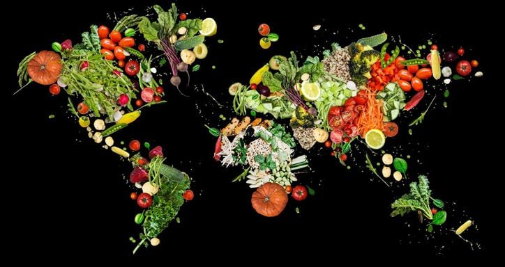 World map made from assorted fruits and vegetables on a black background.