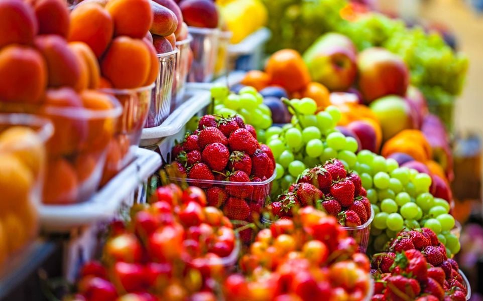 Fruit on store shelves highlighting strawberries and grapes and nectarines