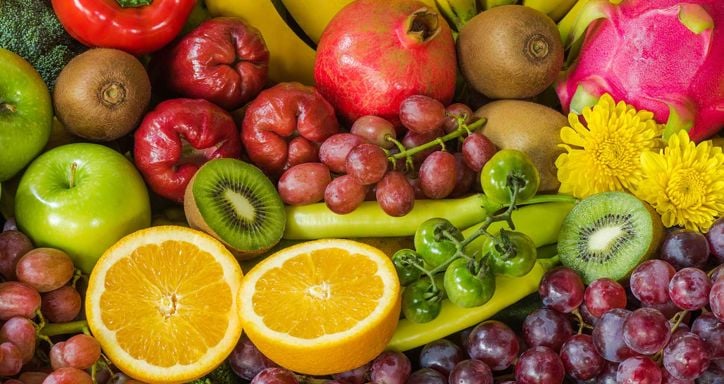 A colorful assortment of fruits and vegetables, including oranges, kiwis, grapes, apples, bananas, a pomegranate, and a dragon fruit.