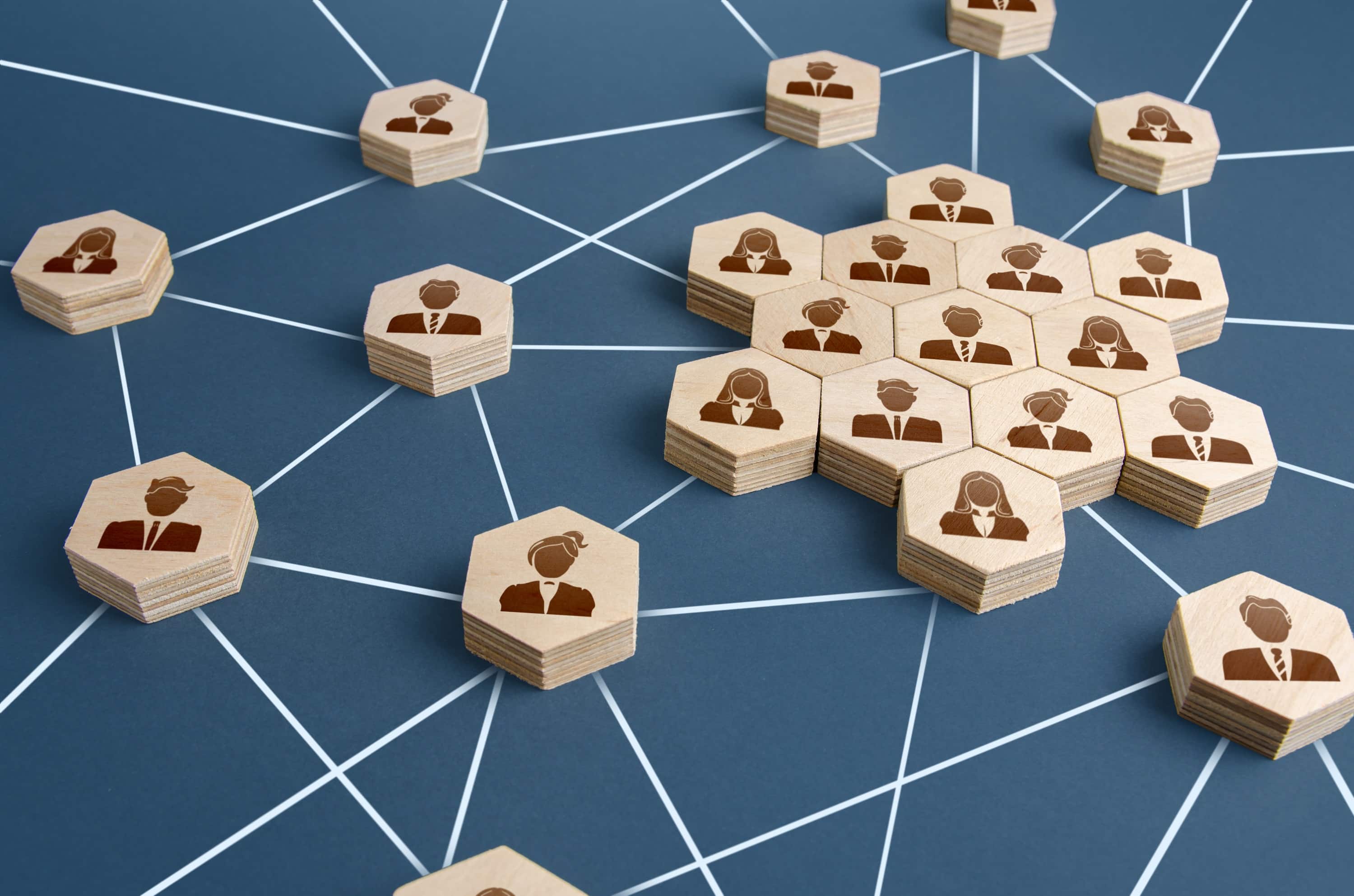 Wooden engraved pieces representing a network of connected people with a large group of employees. 